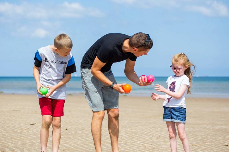 Dad and two children playing a game on the beach