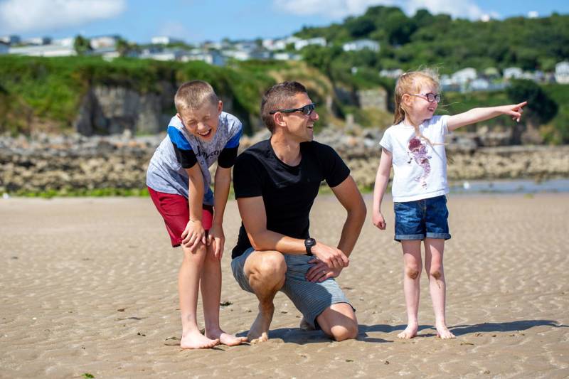 Dad and two children laughing and smiling at the beach